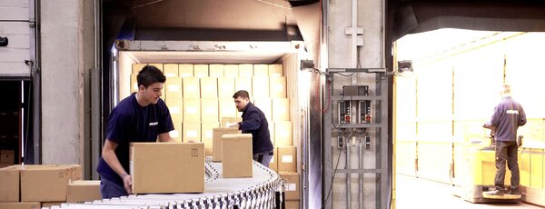 Mitarbeiter in einer Umschlaghalle beim LKW einräumen